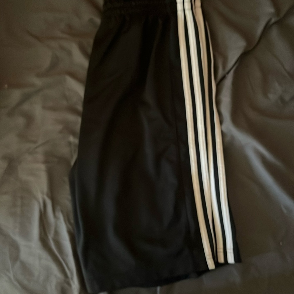 A pair of black with white stripes adidas gym shorts